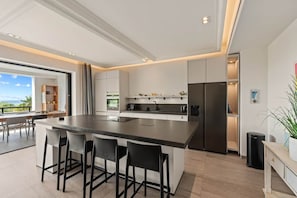 A modern kitchen with a central island, bar stools, and a built-in refrigerator. - NEW: The Shore 16 Beachfront on Blue Bay Beach (Sint Michiel)