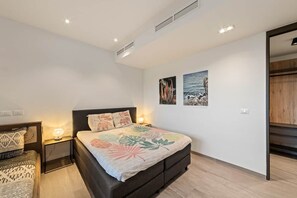 A bedroom with a bed, nightstands, and wall art. - NEW: The Shore 16 Beachfront on Blue Bay Beach (Sint Michiel)