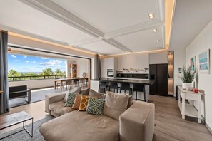A modern living room with a sofa, a dining area, and a kitchen. - NEW: The Shore 16 Beachfront on Blue Bay Beach (Sint Michiel)