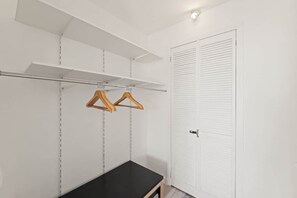Ein Schrank mit Kleiderstange und Sitzbank.