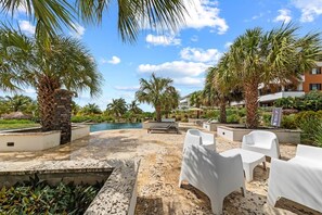 A poolside area with white lounge chairs, palm trees, and a clear sky. - NEW: Shorefront Suite on the Blue Bay Beach (Sint Michiel)