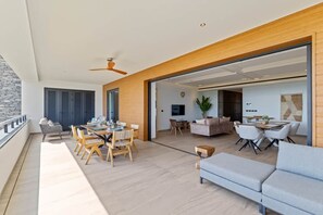 Un balcon spacieux avec un coin repas, un canapé et un téléviseur dans la pièce adjacente.