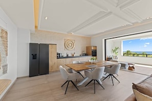 A modern kitchen with a dining area, a large window with a view, and a minimalist design. - NEW: The Shore Beachfront Blue Bay Resort 3 BDR (Sint Michiel)