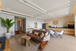 A modern living room with a sofa, chairs, a coffee table, and a dining area with a table and chairs. - NEW: The Shore Beachfront Blue Bay Resort 3 BDR (Sint Michiel)