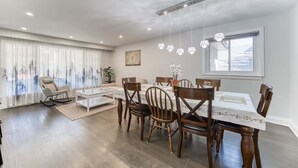Uma sala de jantar moderna com uma mesa posta para quatro pessoas, rodeada por cadeiras de madeira.