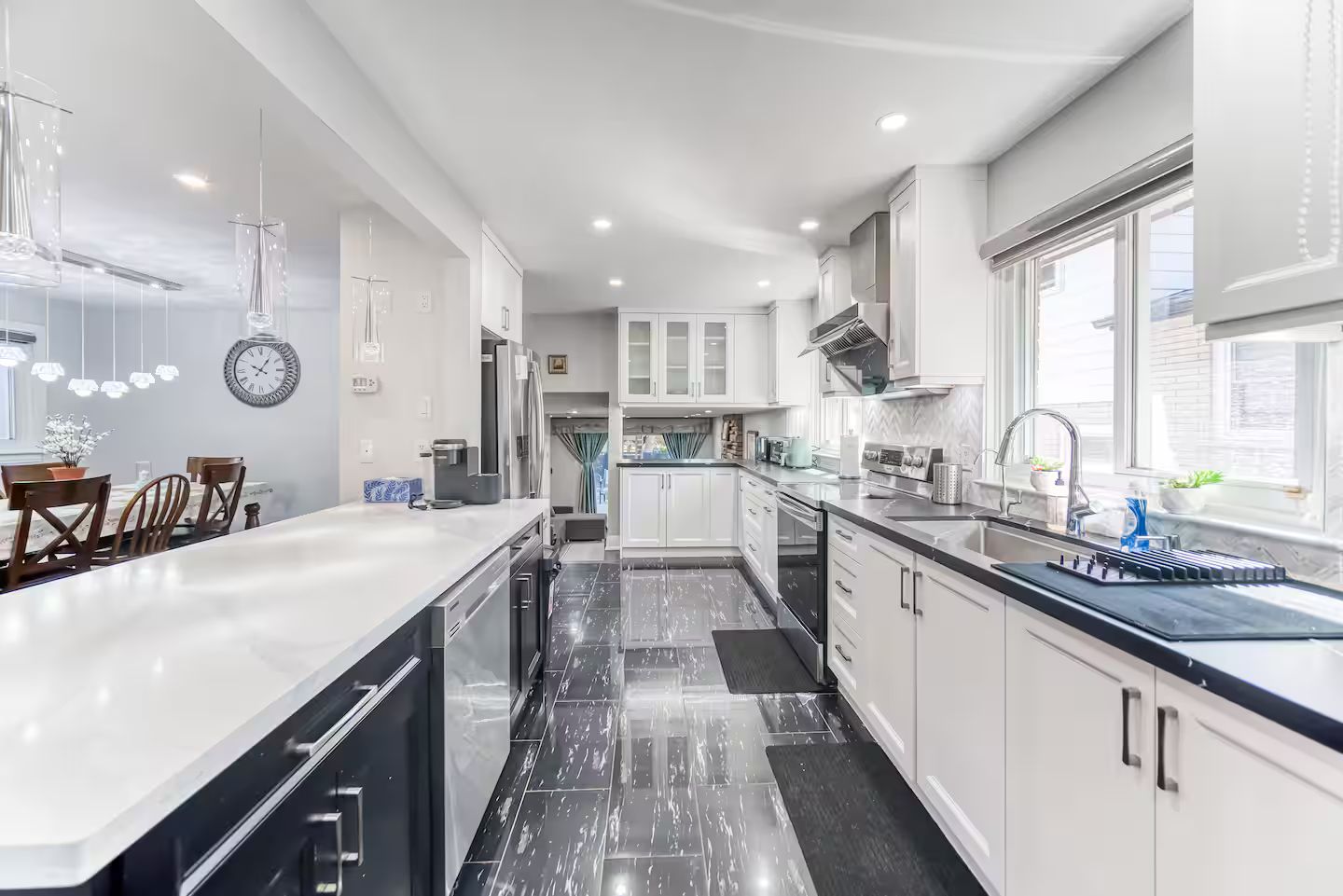 A modern kitchen with white cabinetry, a black countertop, and a large island.