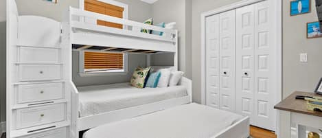A bedroom with a bunk bed, a desk, and a wardrobe.