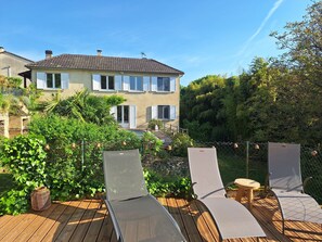 Une maison à deux étages avec un balcon, entourée de verdure.
