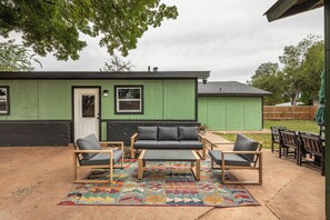 A green house with a patio area featuring a sofa set and chairs. - The Big Country Cactus – Spacious 4BR Home Near Dyess AFB, Job Sites & Colleges (Abilene)