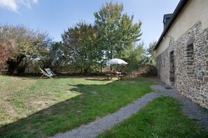 Un cortile lastricato con erba, un muro di pietra, un tavolo da picnic e un'altalena.