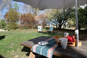 An outdoor picnic setup with a table, a blanket, a teapot, and a cup. - BiâO Gîte en Cotentin Holiday Home with Private Terrace, Garden, and Wi-Fi (Bretteville-sur-Ay)
