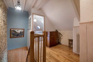 A room with wooden flooring, a wooden staircase, a painting on the wall, and a window with a view. - BiâO Gîte en Cotentin Holiday Home with Private Terrace, Garden, and Wi-Fi (Bretteville-sur-Ay)