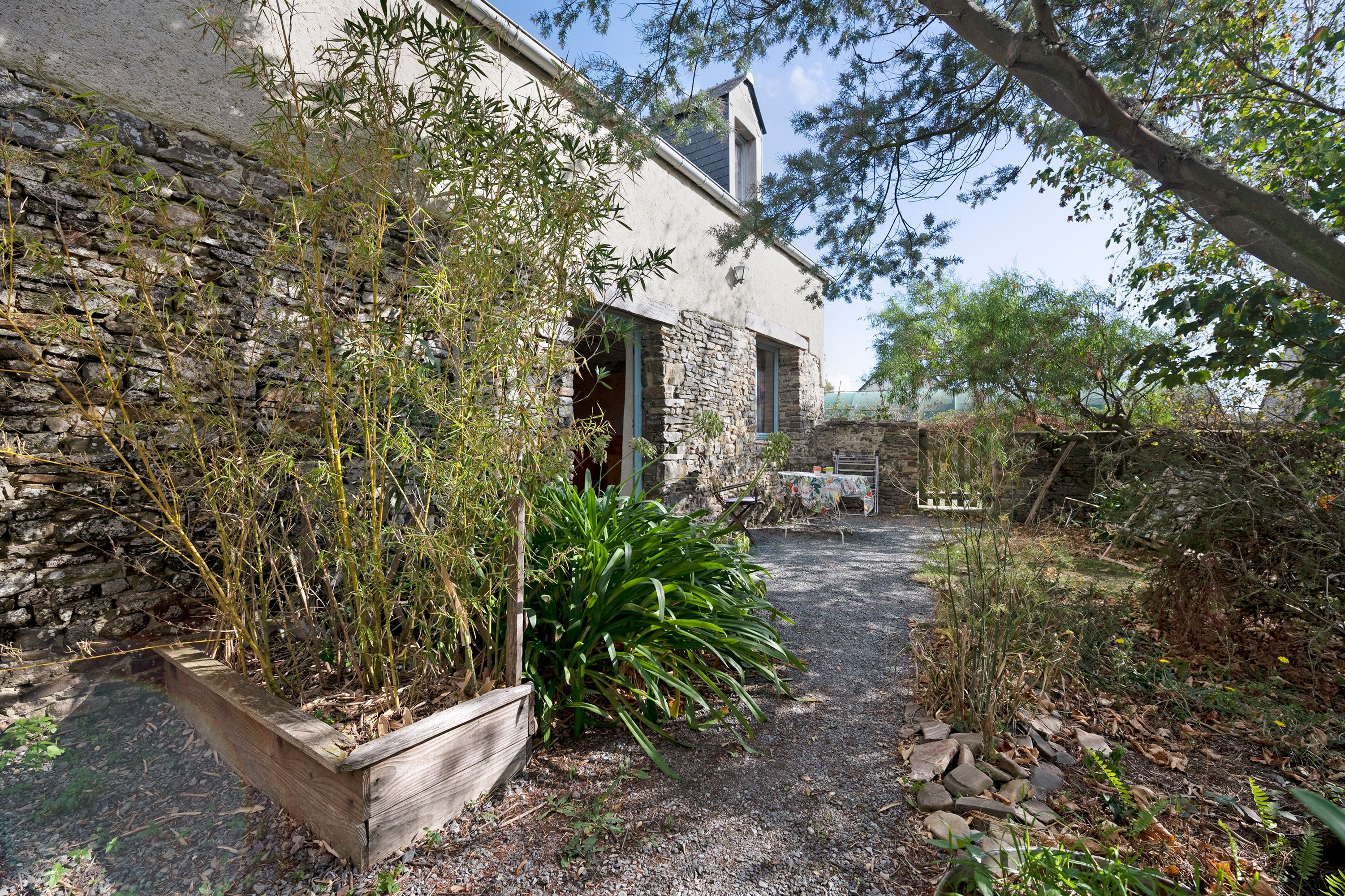 Un bâtiment rustique en pierre, avec un chemin de gravier menant à une terrasse en bois.
