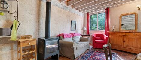 A cozy living room with a fireplace, a sofa, a red chair, and a wooden cabinet.
