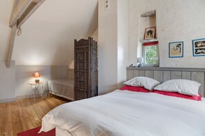 A bedroom with a wooden bed, a nightstand with a lamp, a window with a view, and a wooden wardrobe. - BiâO Petitgîte holiday home with terrace, shared garden, and Wi-Fi (Bretteville-sur-Ay)
