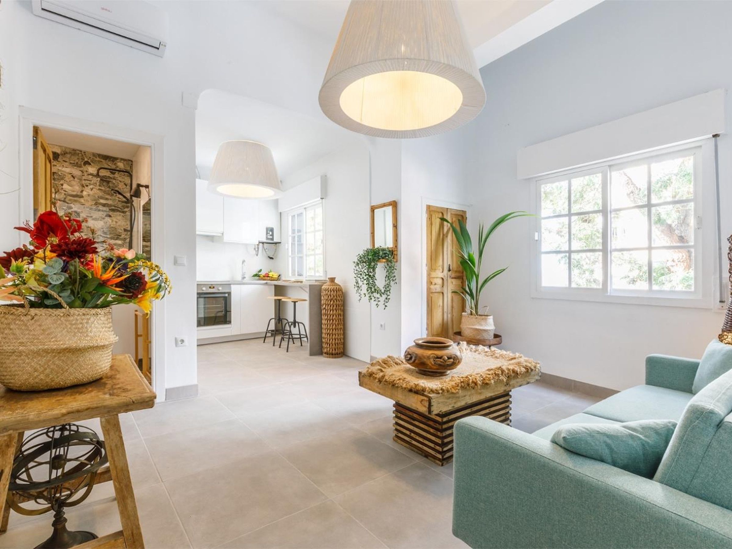 Una sala de estar moderna con un sofá, una mesa con un florero y una cocina al fondo.