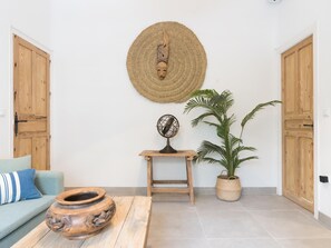 A room with a round woven wall hanging, a wooden table with a pottery piece, a potted plant, and a small table with a globe. - Cozy 2-Bed Apartment in Málaga with Modern Amenities and Central Location (Málaga)
