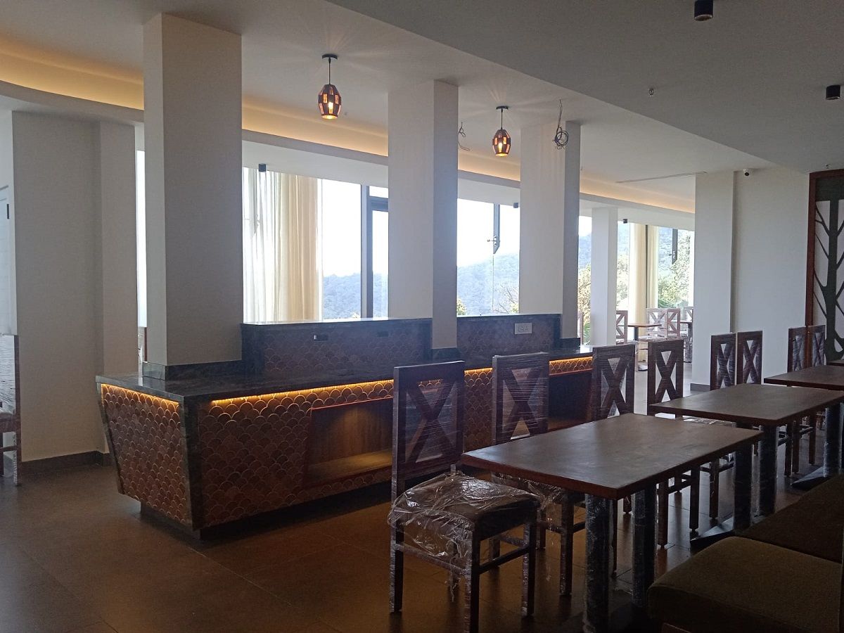 A restaurant interior with a long counter, cushioned seating, and pendant lighting.