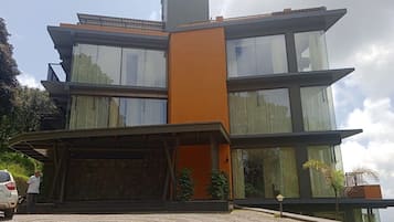 A modern multi-story building with a flat roof, large windows, and a prominent orange accent wall.