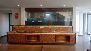 A reception area with a counter, seating, and a staircase in the background. - Soul by Araiya, Paithalmala, A Vihaara Resort & Spa (Kannur)