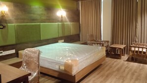 A hotel room with a large bed, a wooden desk, a chair, and a small table. - Soul by Araiya, Paithalmala, A Vihaara Resort & Spa (Kannur)