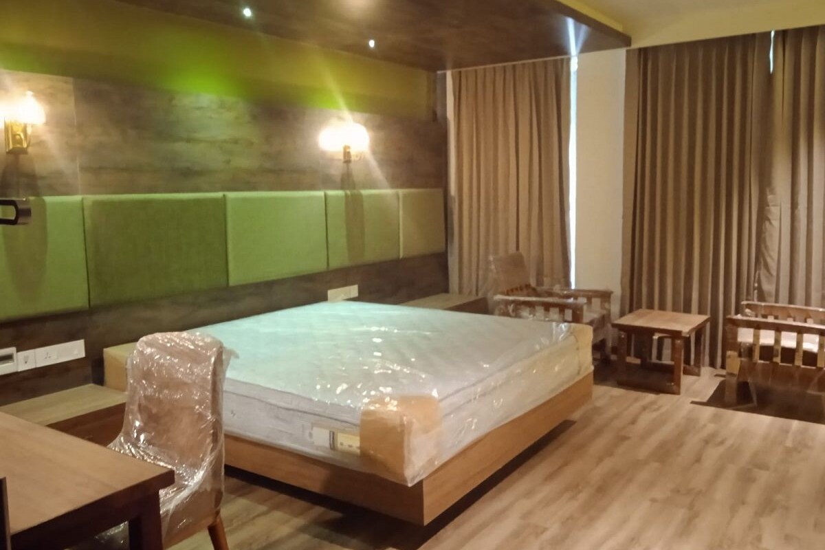 A hotel room with a large bed, a wooden desk, a chair, and a small table.