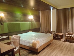 A hotel room with a large bed, a wooden desk, a chair, and a small table. - Soul by Araiya, Paithalmala, A Vihaara Resort & Spa (Kannur)