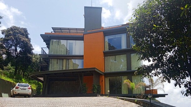 A modern two-story house with a paved driveway and a white car parked in the driveway. - Soul by Araiya, Paithalmala, A Vihaara Resort & Spa (Kannur)