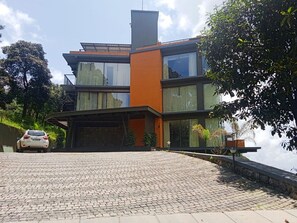 A modern two-story house with a paved driveway and a white car parked in the driveway.