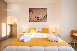 Una camera d'albergo con un letto, comodini, una sedia e un'opera d'arte appesa al muro.