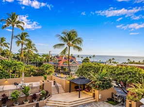 A resort with a pool, outdoor seating, and a view of the ocean. - Kona Pacific C421 | Walk to Aliʻi Drive & Beach (Kailua-Kona)