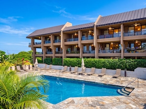 A hotel with a swimming pool, multiple balconies, and outdoor seating. - Kona Pacific C421 | Walk to Aliʻi Drive & Beach (Kailua-Kona)