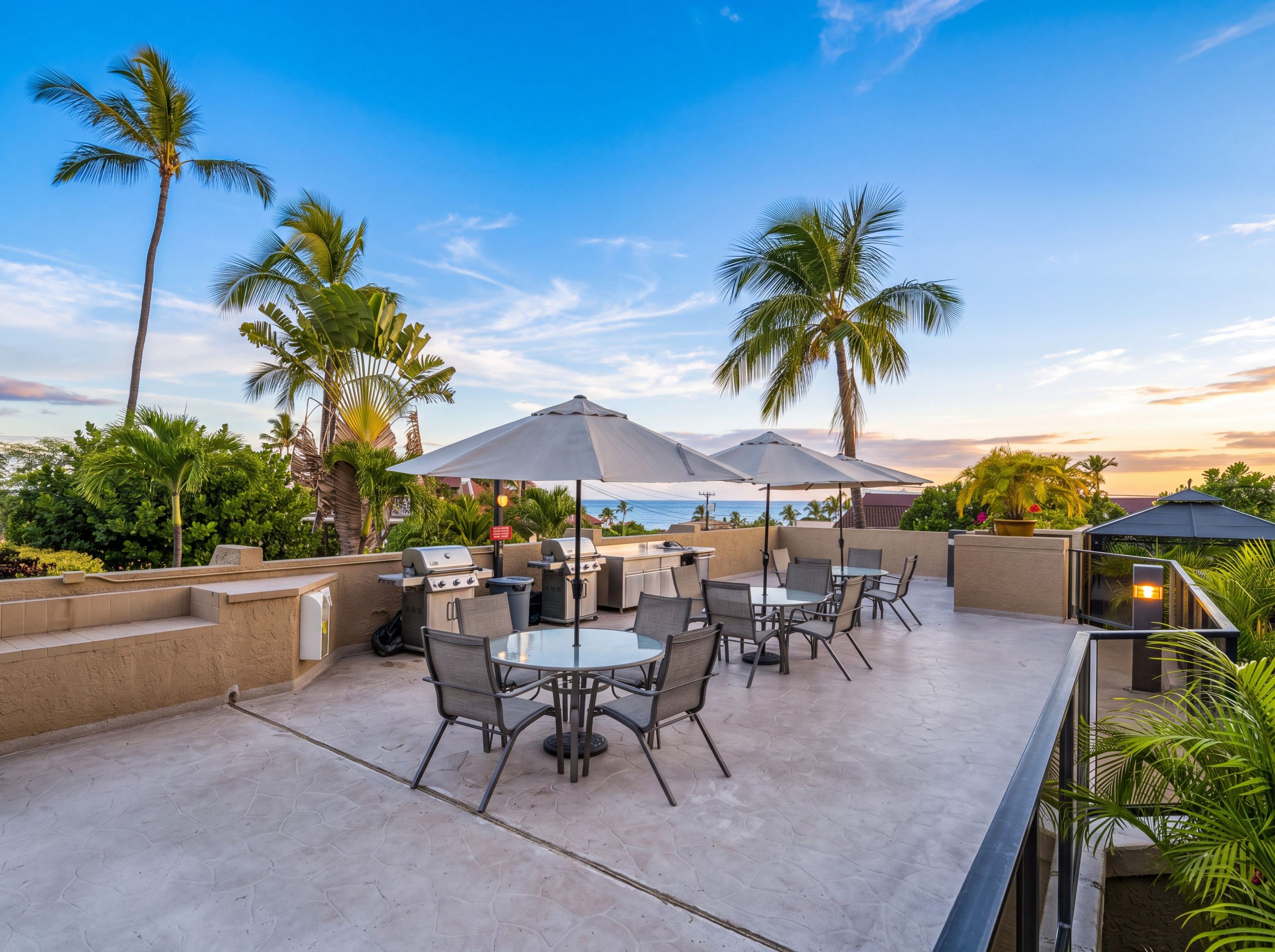 An outdoor patio with a barbecue area, seating, and umbrellas.