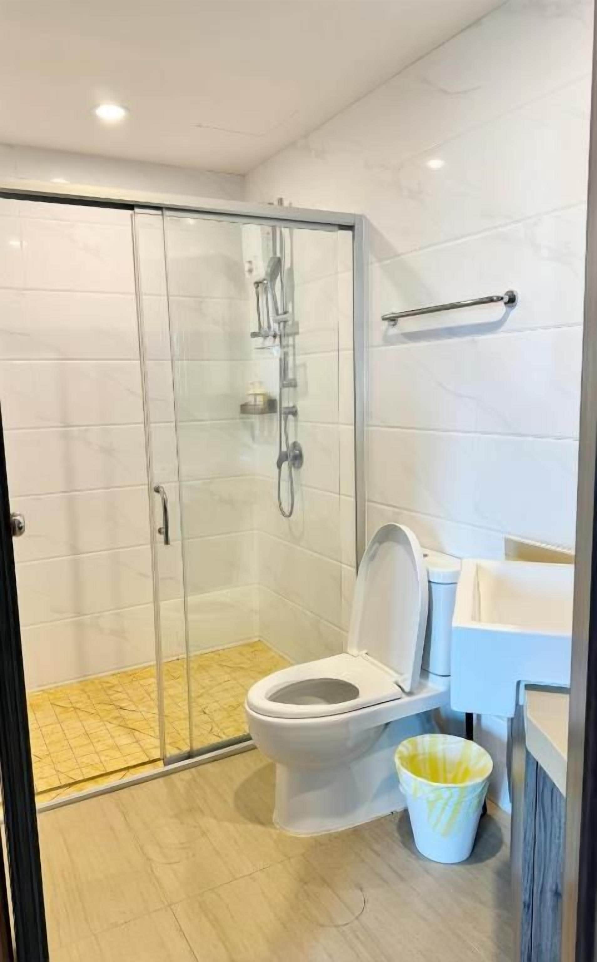 A modern bathroom with a glass-enclosed shower, a toilet, and a sink.