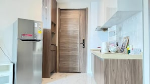 A modern kitchen with a built-in refrigerator, wooden cabinets, and a white countertop. - Artisan Ratchada Condo Bangkok (Krung Thep Maha Nakhon)