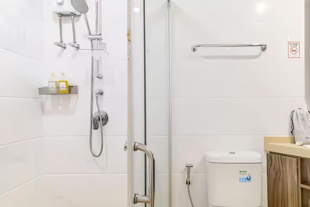 Ein modernes Badezimmer mit einer Duschkabine aus Glas, einem Handtuchhalter und einer Seifenspender.