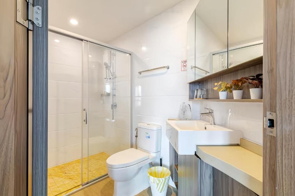A modern bathroom with a glass shower enclosure, a white toilet, and a sink with a mirror above.