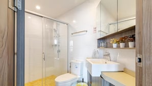 A modern bathroom with a glass shower enclosure, a white toilet, and a sink with a mirror above. - Artisan Ratchada Condo Bangkok (Krung Thep Maha Nakhon)