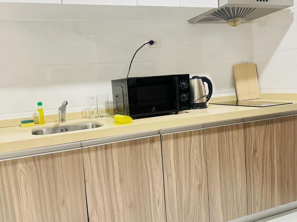 A kitchen with a microwave, kettle, and a wooden countertop.