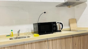 A kitchen with a microwave, kettle, and a wooden countertop. - Artisan Ratchada Condo Bangkok (Krung Thep Maha Nakhon)