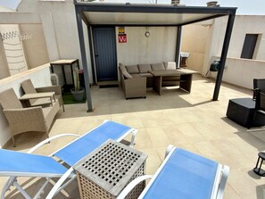 An outdoor patio area with a covered seating area, a table, and a chair. - Apartment 'CasaMar El Cotillo' with Sea View, Wi-Fi and Air Conditioning (El Cotillo)