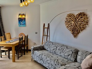 Un coin repas avec une table en bois, des chaises et un élément décoratif mural en forme de cœur.