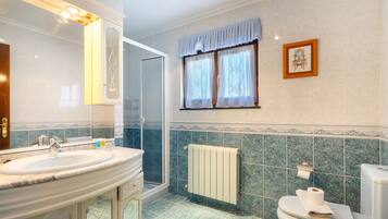 Un bagno con doppio lavandino, doccia, toilette e finestra con tende.