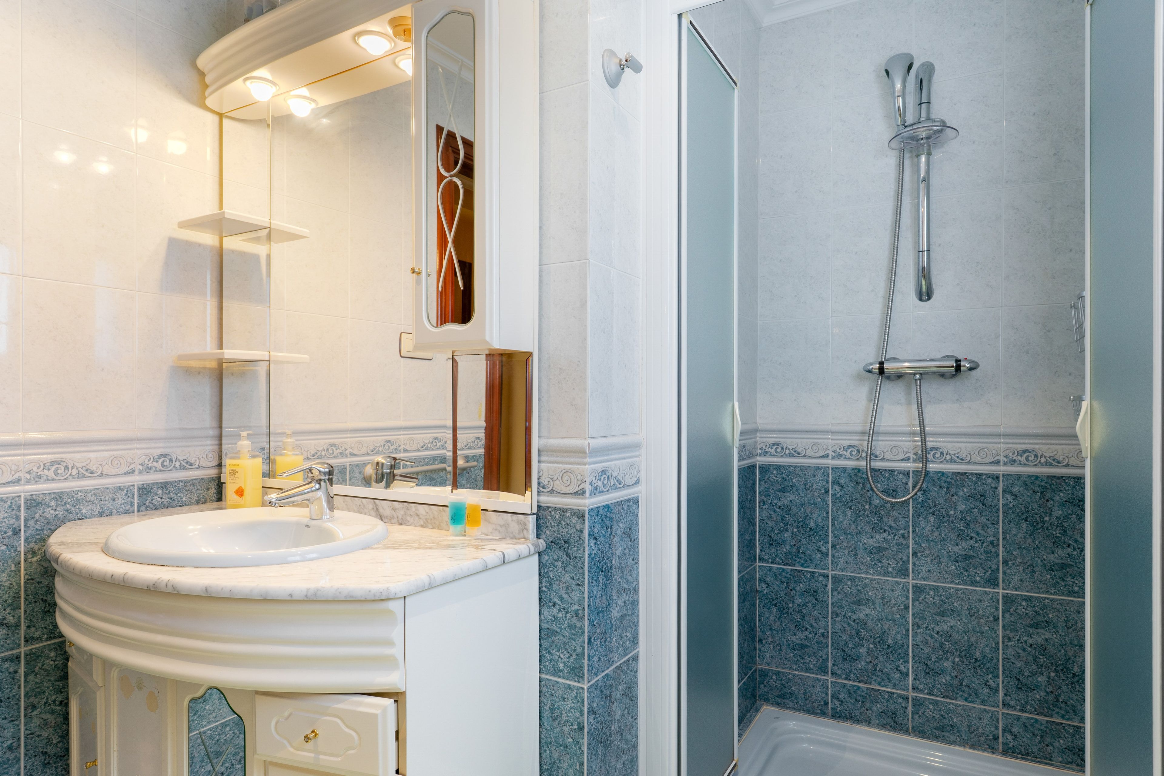 Een badkamer met een wastafel, spiegel en douche.