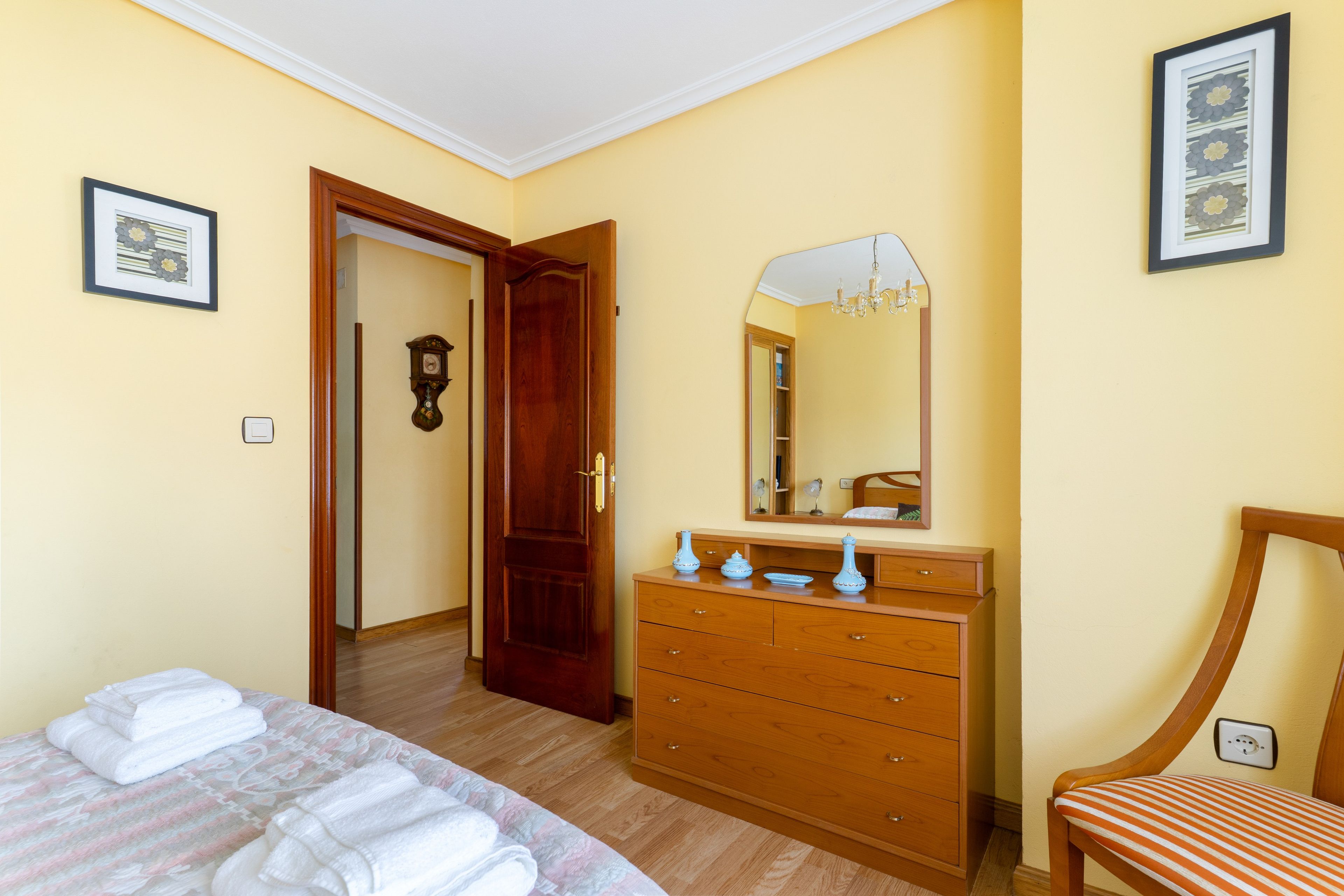 Una habitación de hotel con cama, cómoda, espejo y silla.