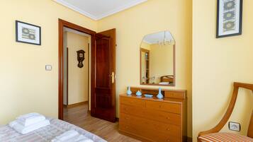 A hotel room with a bed, a dresser, a mirror, and a chair.