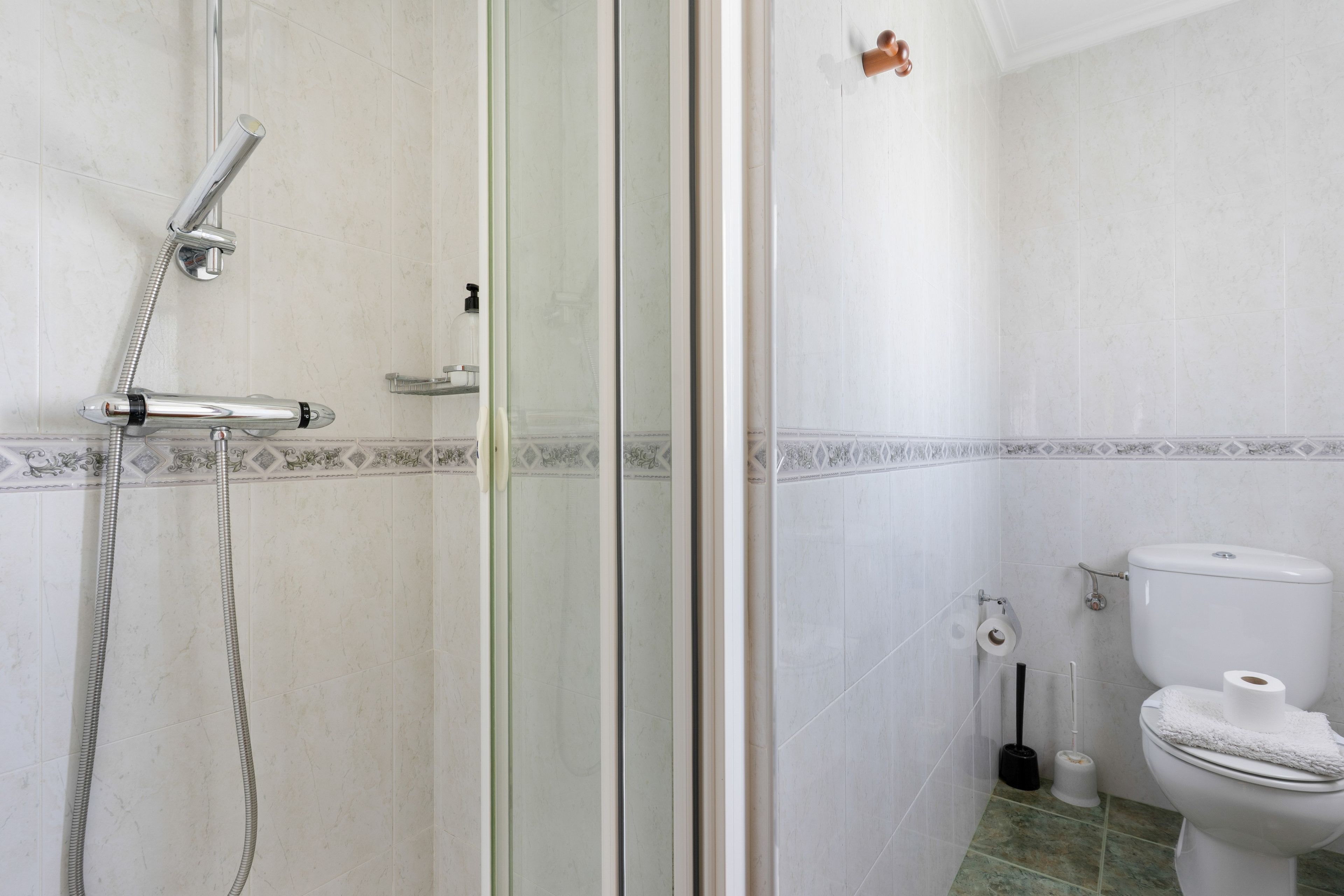 Un baño con ducha, inodoro y puerta de vidrio.