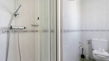 Un baño con ducha, inodoro y puerta de vidrio.