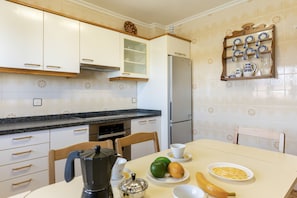 A kitchen with white cabinets, a black countertop, and a refrigerator.