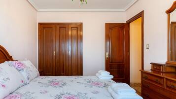 Un dormitorio con una cama, un armario de madera, un espejo y una araña.